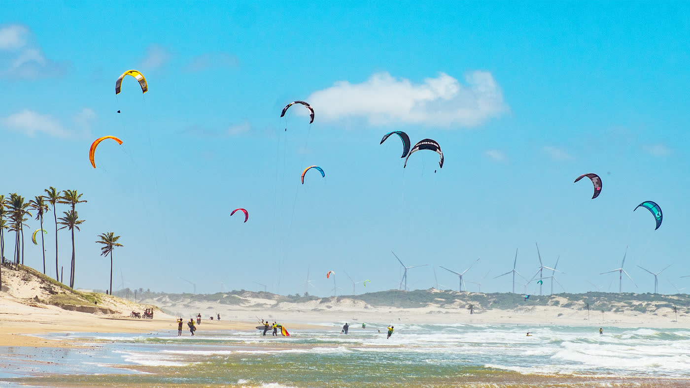Coqueiros e dunas de um pico cearense, kites no ar e torres de vento no horizonte