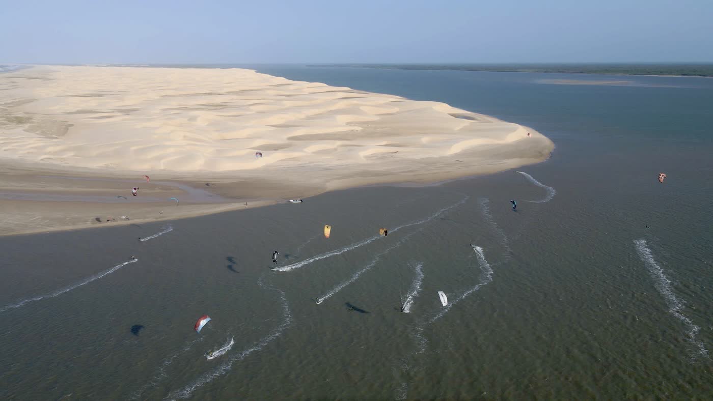 Vista aérea de um banco de areia com velejadores atravessando a água
